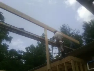 Carpenter setting a ridge beam over a new addition frame — Ice Dam Removal by Roofing Brothers in Aplington