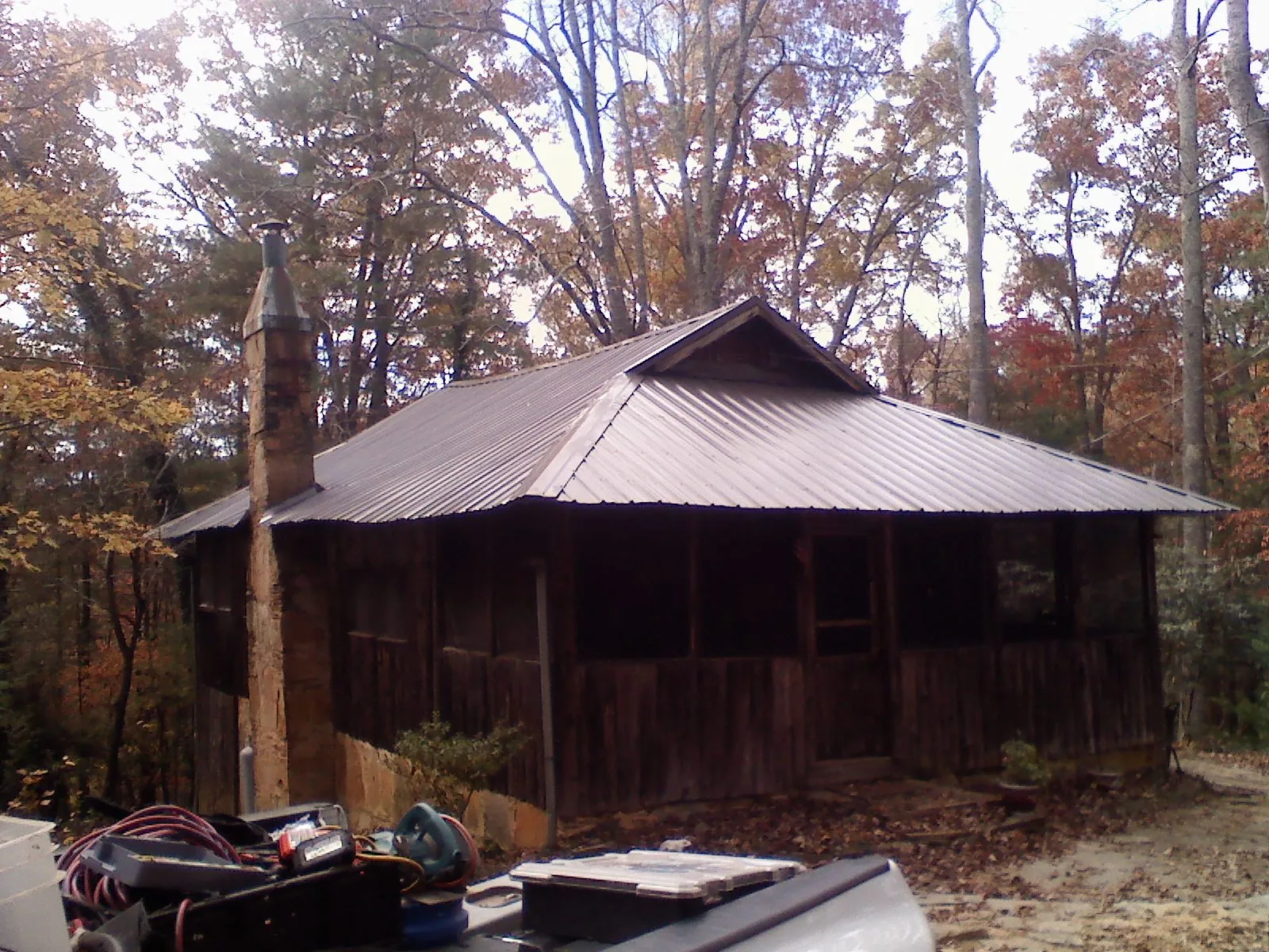 Brown metal hip roof on an old cabin with a stone chimney in Aplington