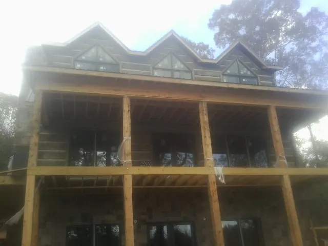 Dormers and porch framing on a large log home under construction — Roof Coating work by our crew in Aplington