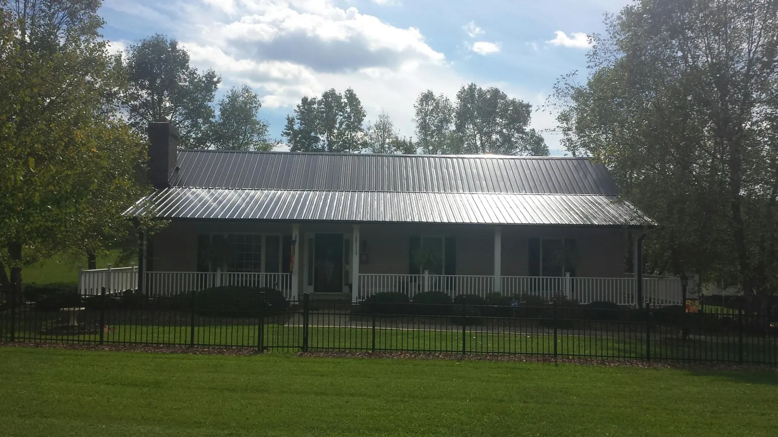 Gray metal roof on a brick ranch with a full width front porch — Gutter Guard Installation work by our crew in Aplington