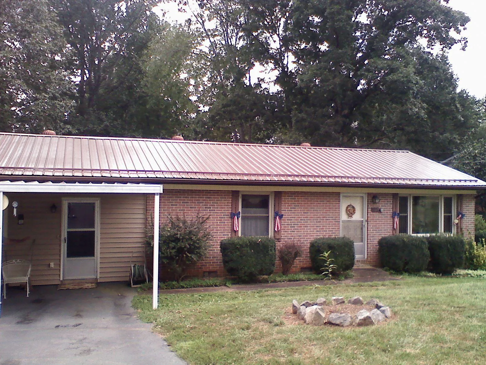 Bronze metal roof and carport on a brick ranch home — Roof Repair work by our crew in Aplington